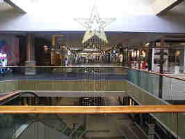 The JCPenney court from the 2nd floor, looking into the mall. A star hangs from the ceiling, along with other holiday decorations. A snack vendor is off to the right.