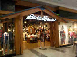 A slightly blurry photo of the Eddie Bauer in the Oak Park Mall. The storefront is log cabin themed, with a wooden entryway leading you into the store.