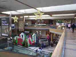The center court of the Oak Park Mall from the 2nd floor. Stars are hanging from the ceiling, with a holiday themed photo booth set up on the bottom floor.