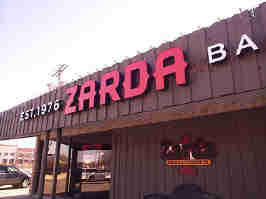 The front of Zarda BBQ. Their red logo is on the front of a brown wood building.