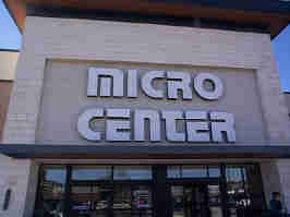 The entrance to the Overland Park Micro Center. The company's logo sits above glass doors, surrounded by white tile and concrete.