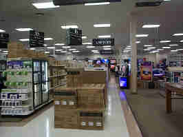 The home computer section of Micro Center. Monitor boxes line the walkway, with shelves of routers to the left and tables of demo systems to the right.